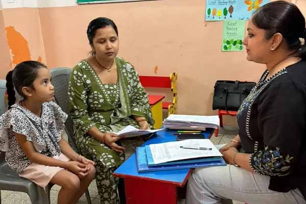 Nursery children colouring and learning letters with their teacher